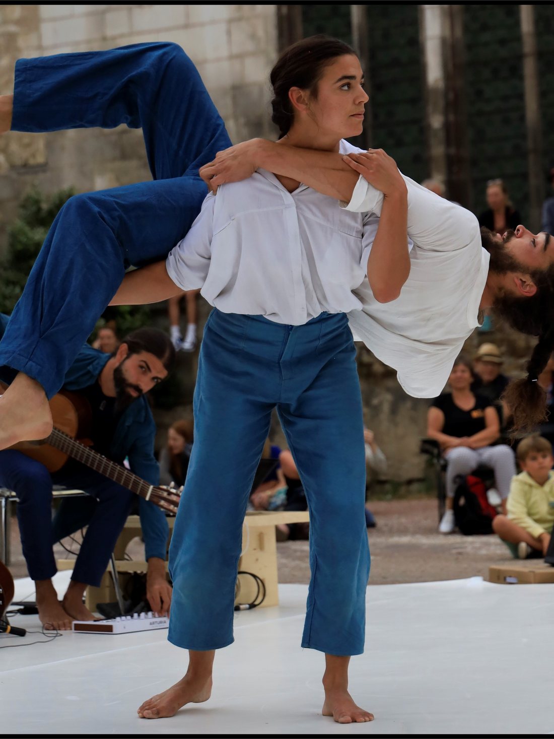Un porté renversé, une acrobate tenue à l'horizontale au-dessus des épaules de son partenaire