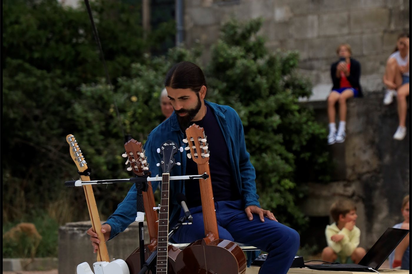 Le musicien assis derrière ses guitares et sa batterie, devant le public