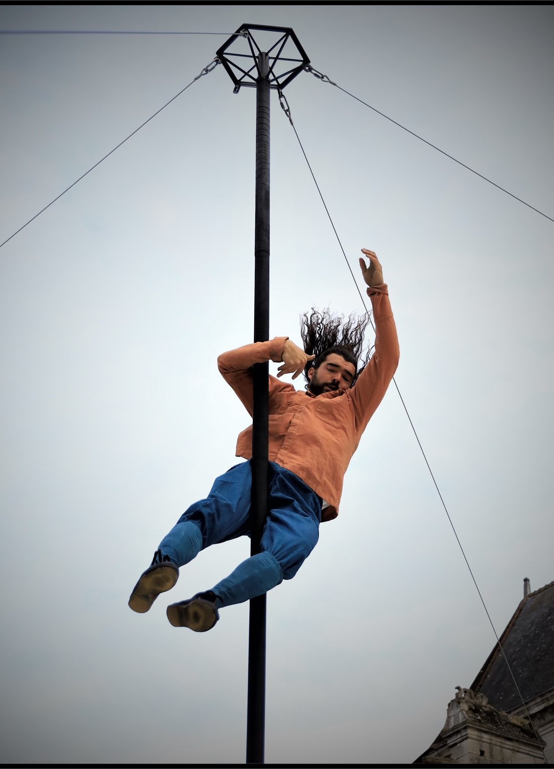 Une acrobate s'élance au sommet du mât chinois, détachée sur un ciel clair