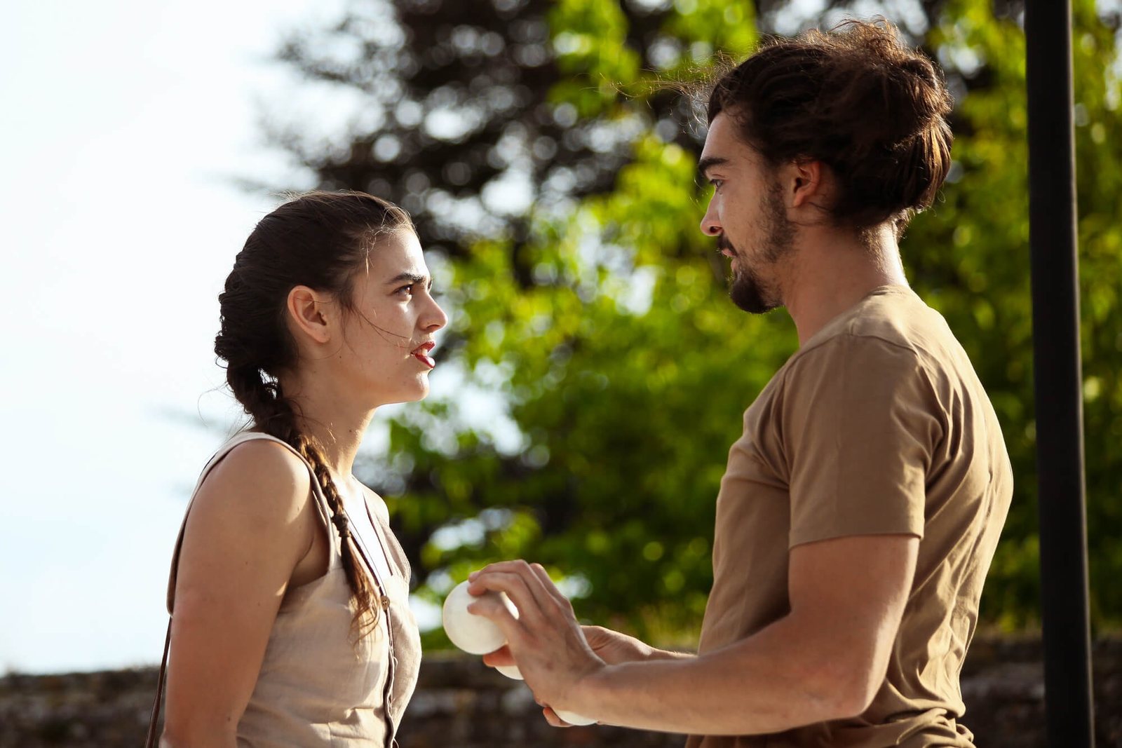 Un acrobate et une acrobate se font face, une balle blanche entre leurs mains